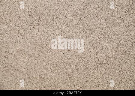 The wall is plastered with beige, coarse plaster. Stock Photo