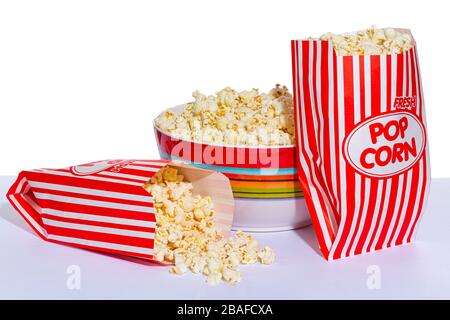 Horizontal shot of a bowl of popcorn with one bag of popcorn leaning against it and a second bag of popcorn laying in front of it with the popcorn spi Stock Photo