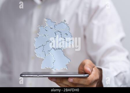 Illustration of the map of Germany connected with dots on top of the phone in the hands of a man Stock Photo