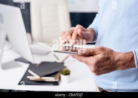 Close-up of unrecognizable man checking email on tablet while waiting for business proposal from business partner Stock Photo
