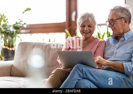 Mature couple using a laptop while relaxing at home Stock Photo