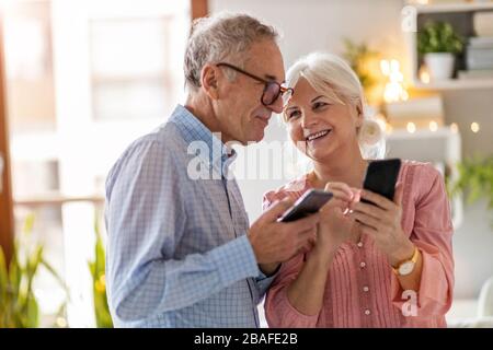 Senior couple looking at a smartphone together at home Stock Photo