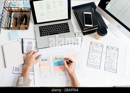 Above view of app interface designer making sticky notes on scheme while planning menu design in office Stock Photo