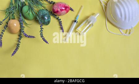 Easter during coronavirus concept. eggs and mask on yellow background. COVID-19 outbreak, celebration and stay home concept.  Top view, flat lay, copy Stock Photo
