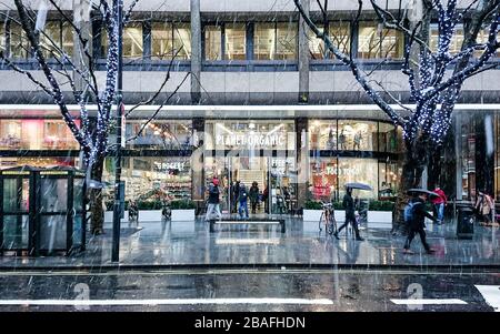 Planet Organic. A busy London street scene with Christmas shoppers on Tottenham Court Road on a cold and snowing winters day. Stock Photo