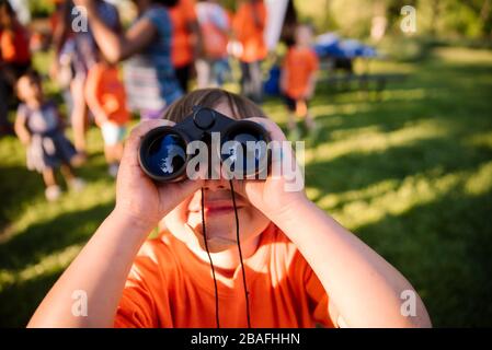 small boy looking through binoculars in a park Stock Photo