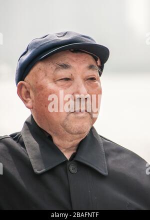 Shanghai, China - May 4, 2010: Closeup of face of older balding senior man with black shirt and black hat. Stock Photo