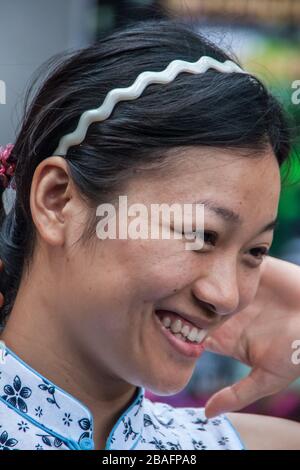 Shanghai, China - May 4, 2010: Portrait closeup of face of smiling woman with long black hair and white headband. Stock Photo