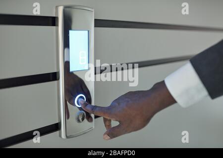 Hand of young African businessman or office worker pressing button on panel to call elevator while coming for work in the morning Stock Photo