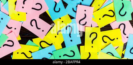 Too Many Questions on wooden background. Pile of colorful paper notes with question marks. top view. Stock Photo