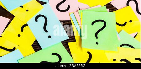 Pile of colorful paper notes with question marks on wooden background. Closeup. Stock Photo