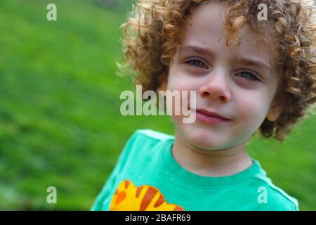 Beautiful boy with green eyes, curly hair and tan skin Stock Photo - Alamy