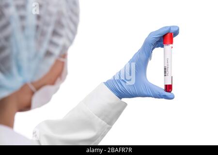 Gloved hand of female virologist in mask and whitecoat holding flask with sample of blood for covid19 test in front of herself Stock Photo