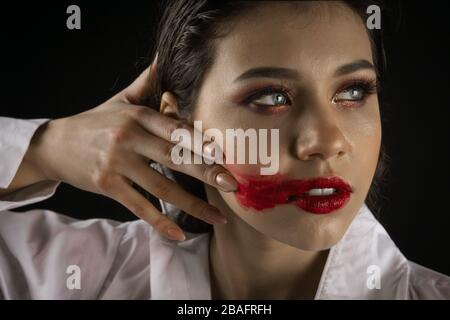 Woman smearing lipstick on face Stock Photo
