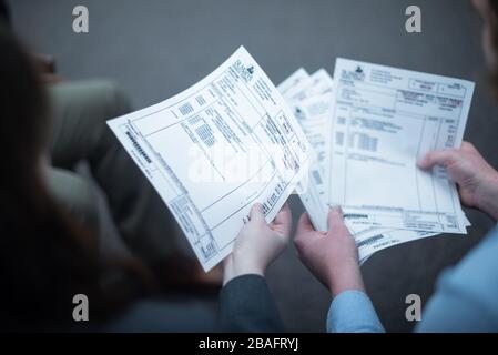 White couple's hands leafing through pile of medical bills Stock Photo