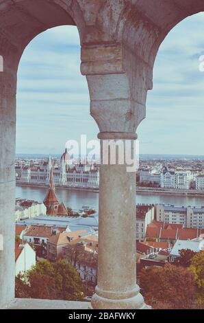Cityscape of Budapest, Hungary photographed through the arch window of the Fishermans Bastion. Hungarian Parliament Building, Orszaghaz, in the far background on the other side of the Danube river. Stock Photo
