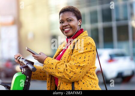Young woman with electric scooter checking her smartphone Stock Photo