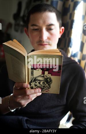 Hackney, London, England, UK. Corona Virus (Covid-19) pandemic. Young man reading 'The Plague' by Albert Camus.