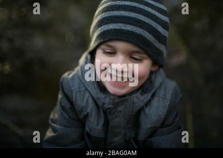 Close up of a young boy's smiling face as he runs. Having fun, winter light. Stock Photo