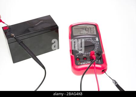 Multimeter instrument measuring battery voltage over a white background Stock Photo