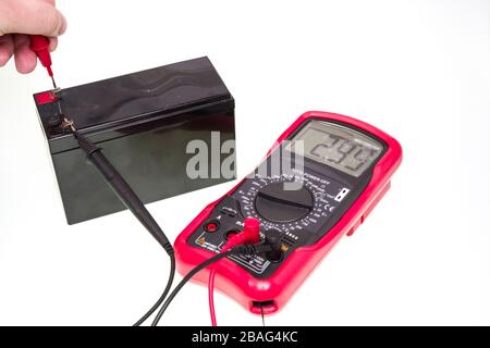 Man measuring voltage of battery with digital multimeter instrument, over a white background Stock Photo