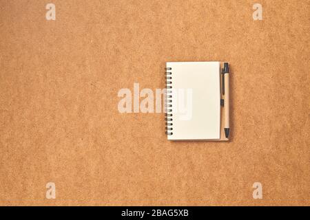 Top view spiral notebook with penc on brown desk background. Copy space. Stock Photo