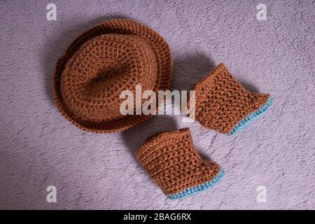 Knitted hat and boots. Knitted shoes and clothes. Booties for babies. Stock Photo