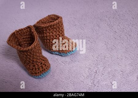 Knitted boots. Knitted shoes. Booties for babies. Made by hands. Stock Photo