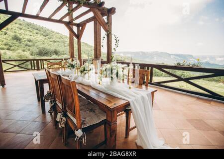 Decorated wedding table for the newlyweds and guests with mountain views. Wedding decor and Floristics. Stock Photo