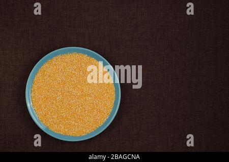 Corn grits polenta in a blue plate on linen background Stock Photo