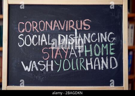 Inscription social distancing stay at home wash your hands. Outbreak Warning. written white chalk on blackboard in connection with epidemic of coronav Stock Photo