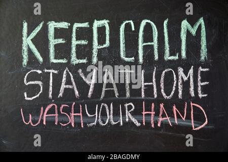 Inscription keep calm stay at home wash your hands. Outbreak Warning. written white chalk on blackboard in connection with epidemic of coronavirus wor Stock Photo