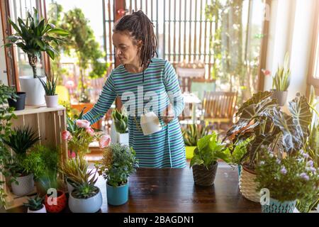 Young woman taking care of her potted plants at home Stock Photo