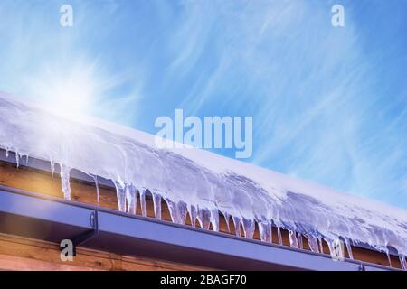 The snow melts from the roof into icicles under the spring sun Stock Photo