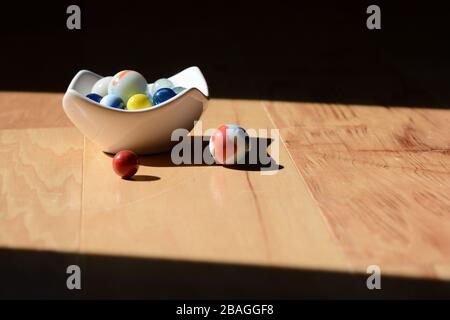 Old-fashioned glass marbles on a wooden floor. Sunshine and shadow. Stock Photo