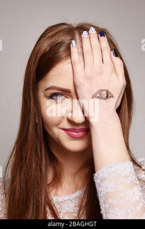 brunette woman with painted eyes on her hand as a symbol of not fair play and double standards gestures, body language, psychology concept Stock Photo