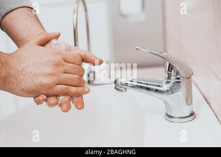 Hand washing with soap in a sink in a public place. Hygiene concept. Washing hands with soap under the faucet with water. Stock Photo