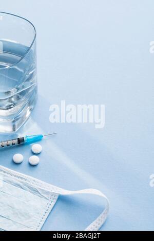 Syringe with pills, water and surgical mask Stock Photo