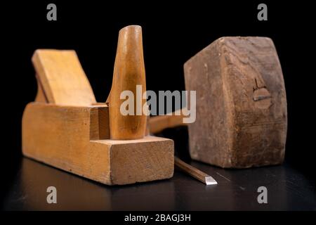 Joiner's planer, wooden hammer and chisel. Carpentry accessories in the workshop. Dark background. Stock Photo