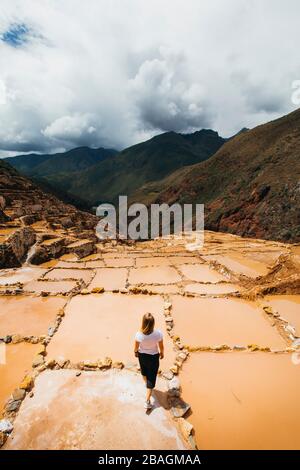Young woman is standing near the famous salt mines in Peru Stock Photo
