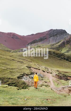 A man in a yellow jacket is standing on a hill in Peru Stock Photo