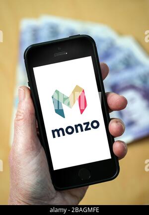 A woman looking at the Monzo Bank logo on a mobile phone. (editorial Use Only) Stock Photo