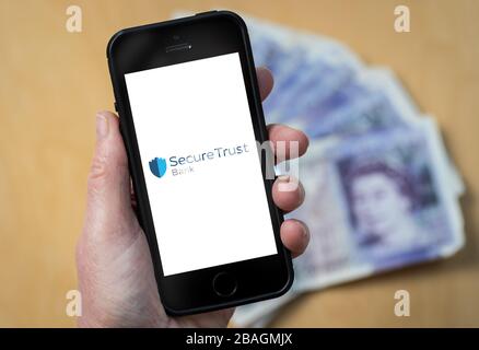 A woman looking at the Secure Trust Bank logo on a mobile phone. (editorial Use Only) Stock Photo