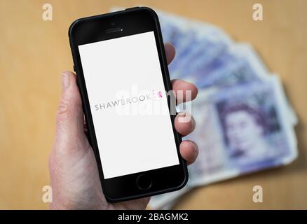 A woman looking at the Shawbrook Bank logo on a mobile phone. (editorial Use Only) Stock Photo