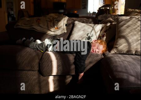Toddler boy sleeping on his stomach on couch at home in pretty light Stock Photo