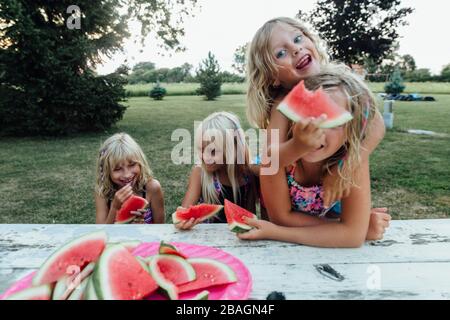 children being silly eating watermelon outside in the summer Stock Photo
