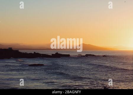 View of the ocean and the coast from the light house in Biarritz at sunset, looking out to the Virgin Mary Statue and Spain. Stock Photo