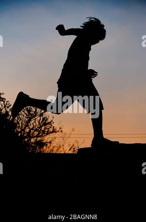 Silhouette playful boy with sky of sunset Stock Photo