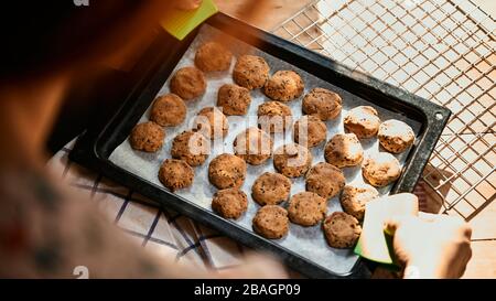 Hand of baker holding the baking tray of sesame cookies Stock Photo