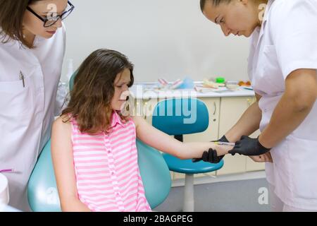 Dentist makes an injection in hand, checks reaction of body to anesthetic preparations Stock Photo